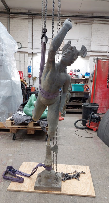 The supporting armature exposed in the statue's calf