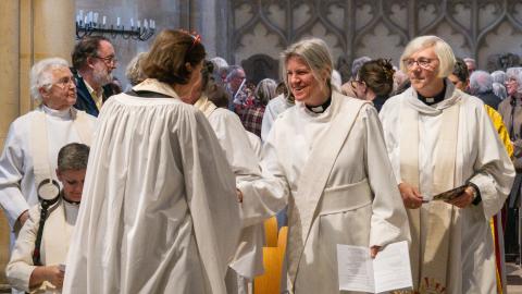 Two robed priests from the 1994 cohort of women shake hands as they exchange the sign of the peace during the service