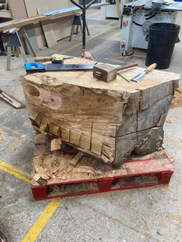 A large sycamore log has begun to be shaped into a plinth. It stands in the Christ Church workshop, with a selection of carpentry tools lying on top of it.