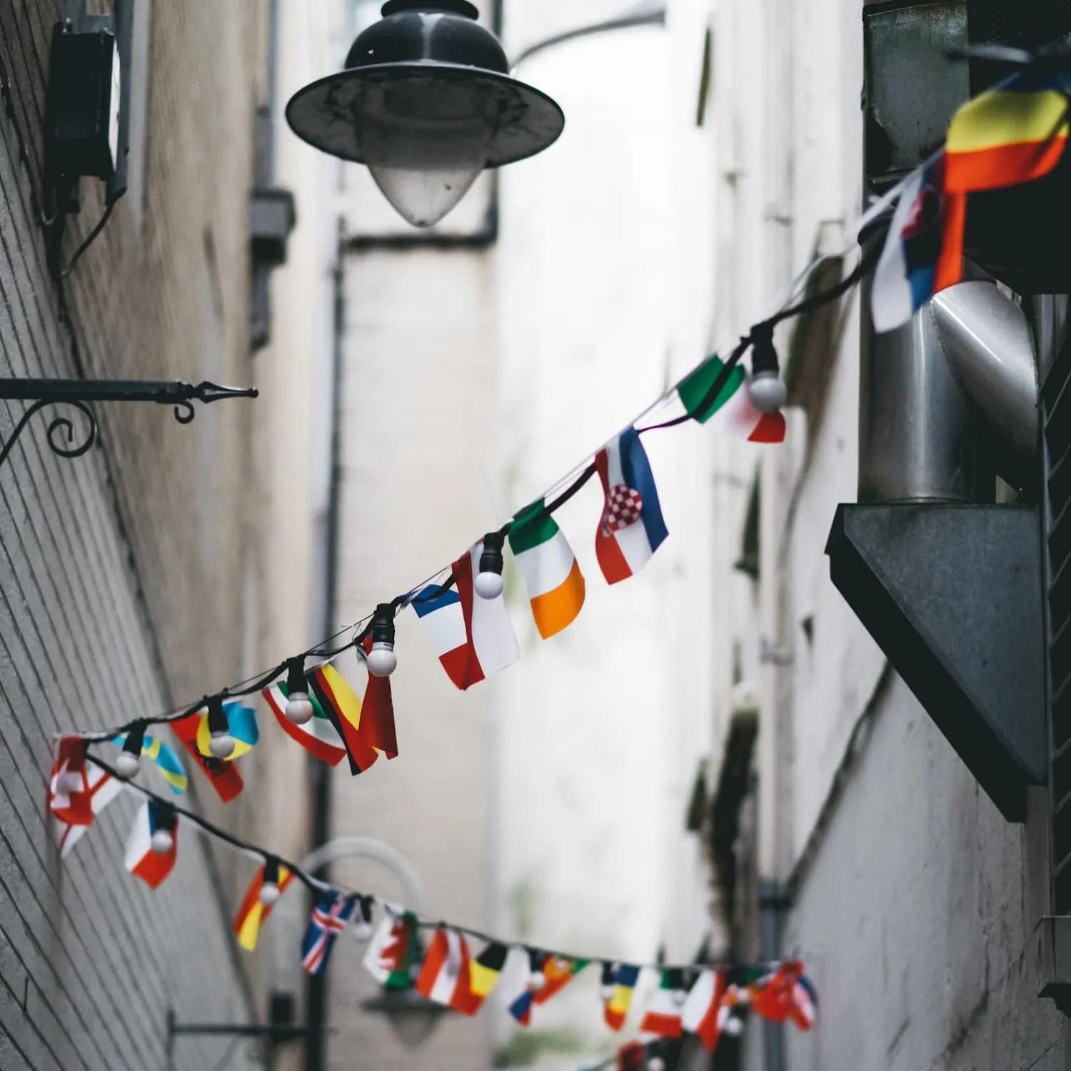 Flags suspended from one side of an alleyway to the other.