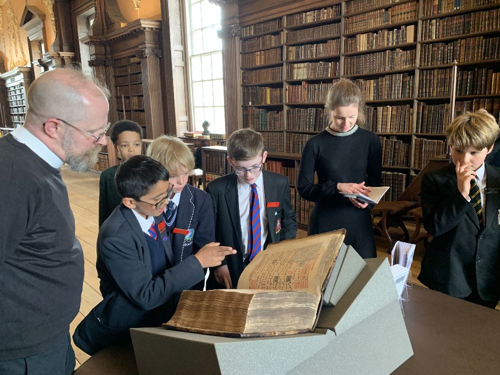 Choristers looking at a book in the upper library