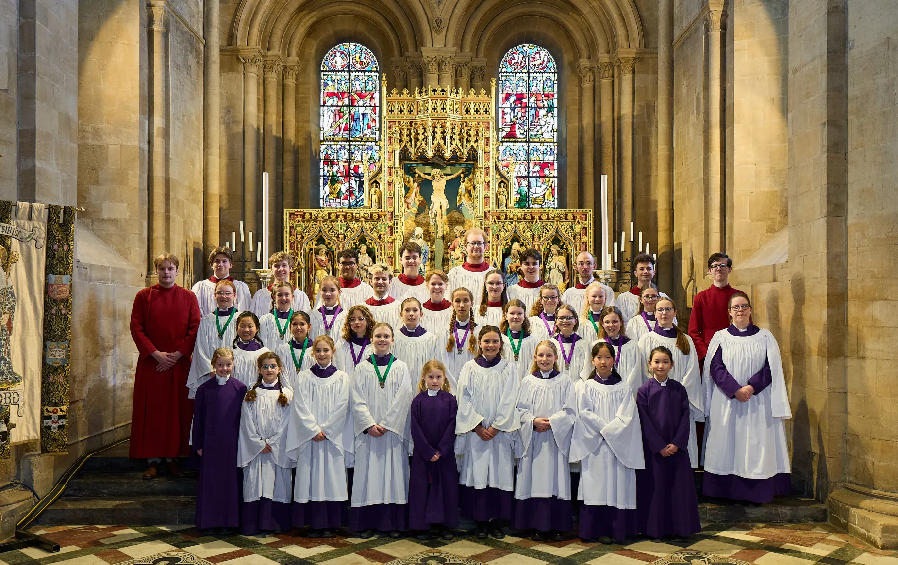 Frideswide Voices, the clerks and organ scholars, arranged in the choir robes in front of the cathedral altar.