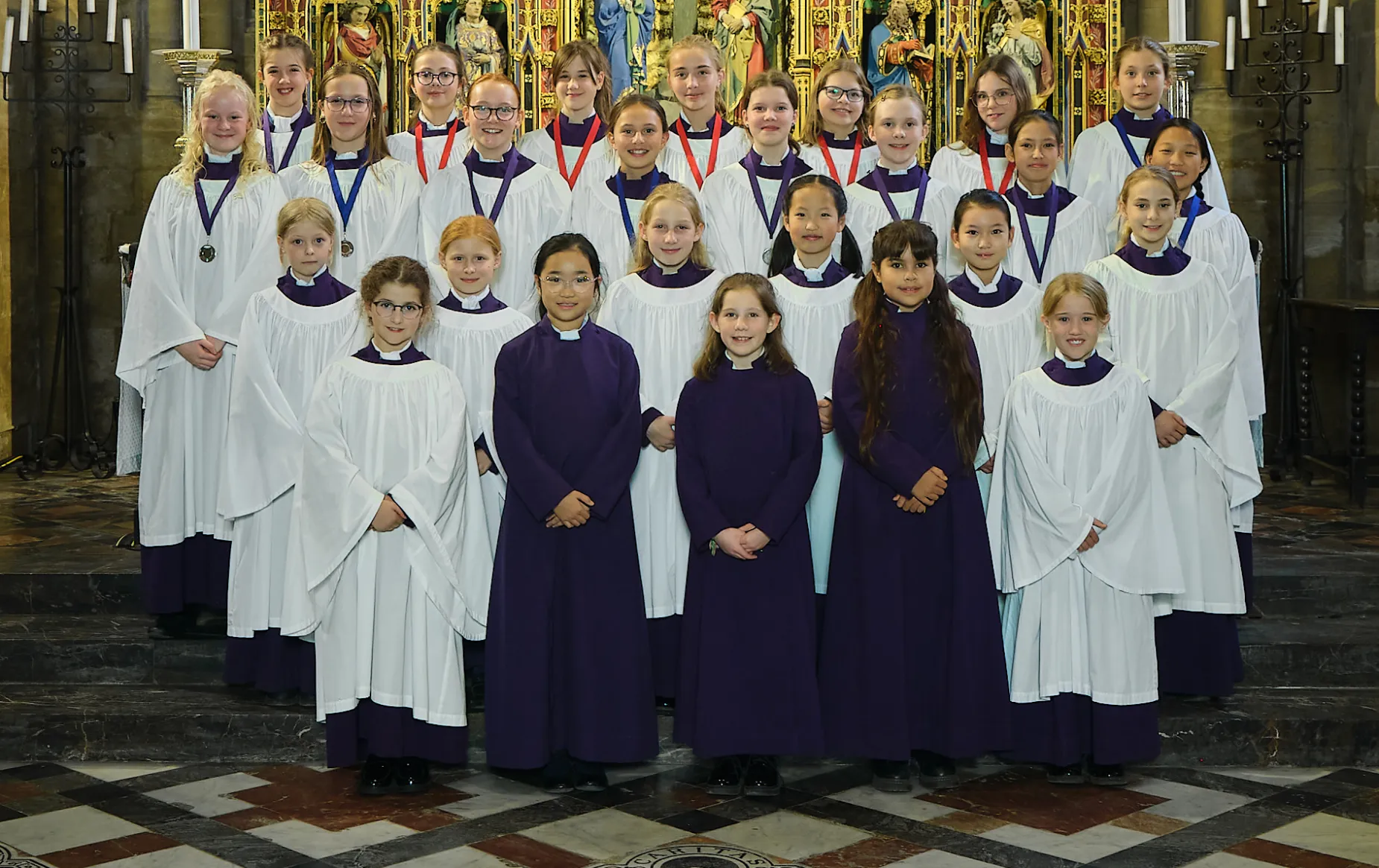 Frideswide Voices choristers in their choir dress gathered by the high altar of Christ Church Cathedral