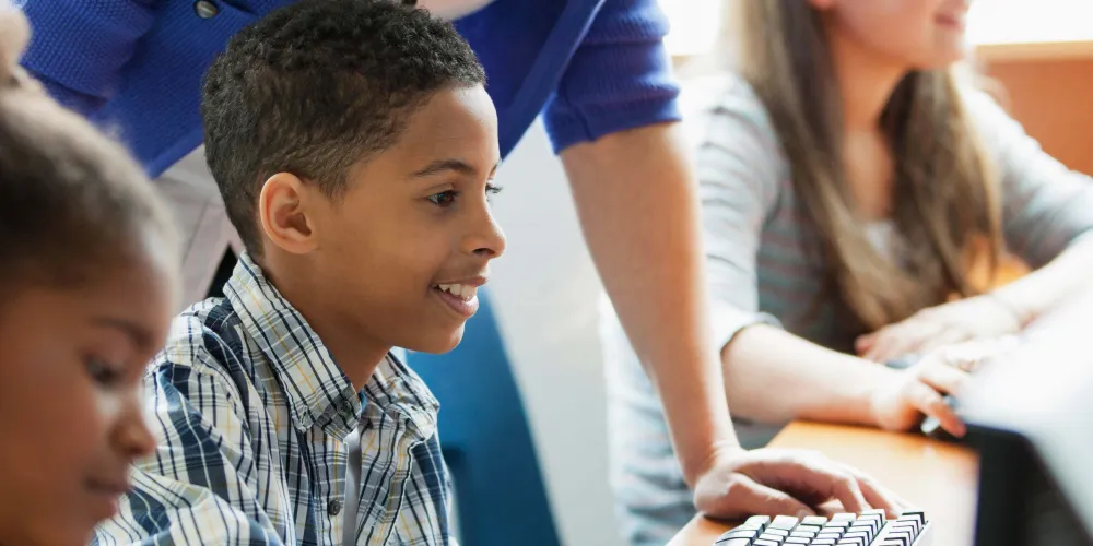 A teacher supporting a schoolchild on the computer