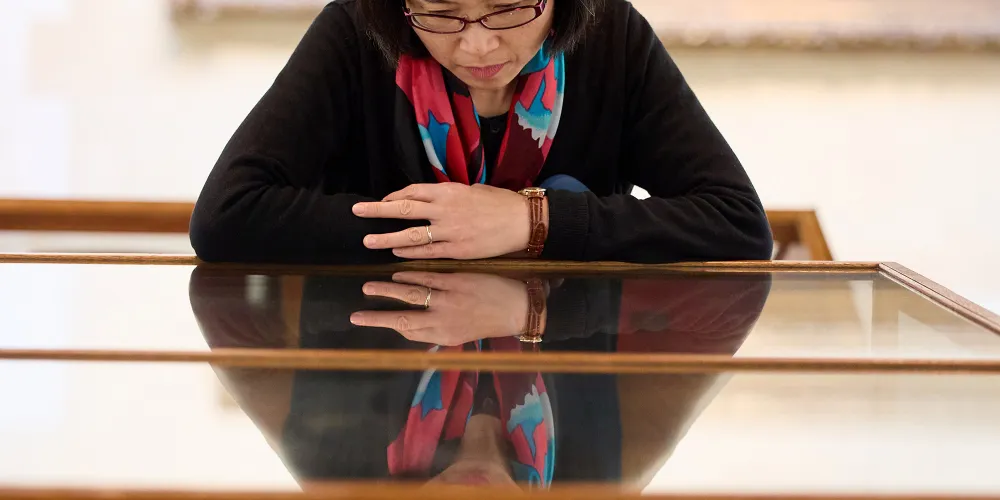 A woman admires an artefact in a glass case in the Picture Gallery