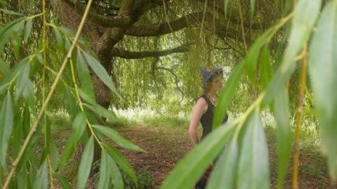 A photograph depicting Lula Flint under a willow tree