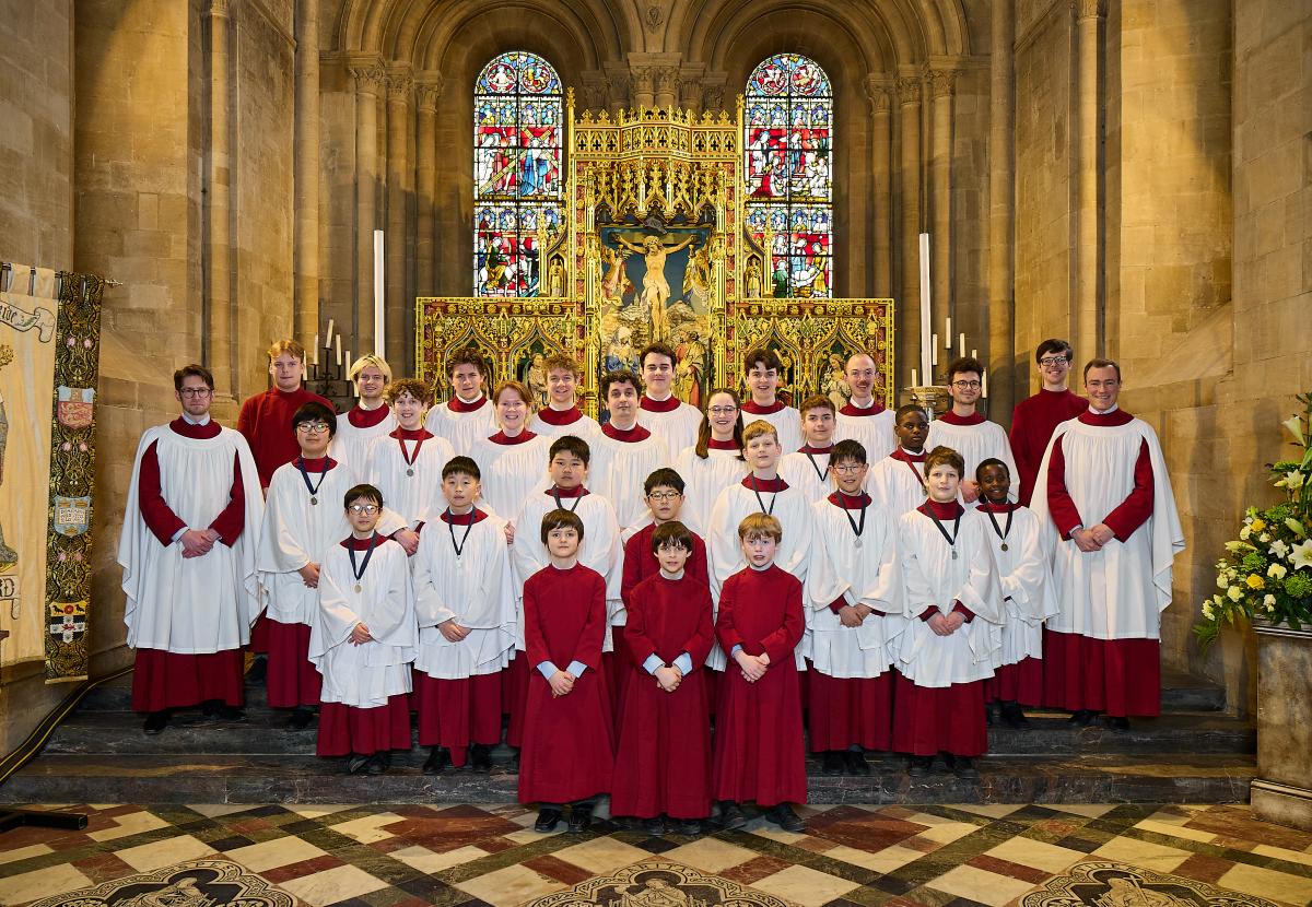 The choir, in their robes, stand in the cathedral sanctuary in a group portrait
