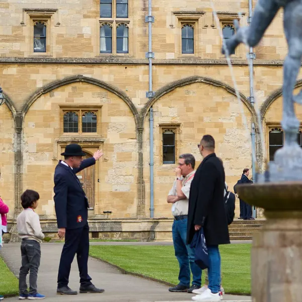 A Custodian with a tour group in Tom Quad