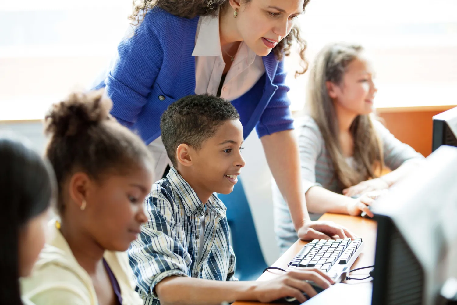 A schoolchild being given assistance on a computer