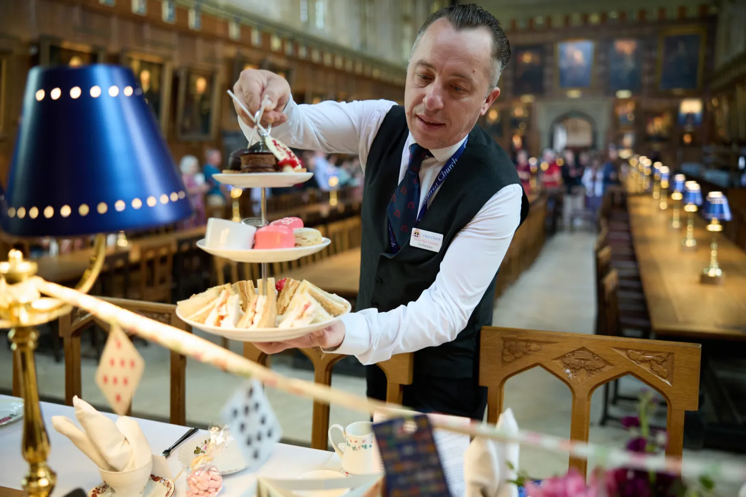 A photo showing a member of staff setting down an afternoon tea stand on high table 