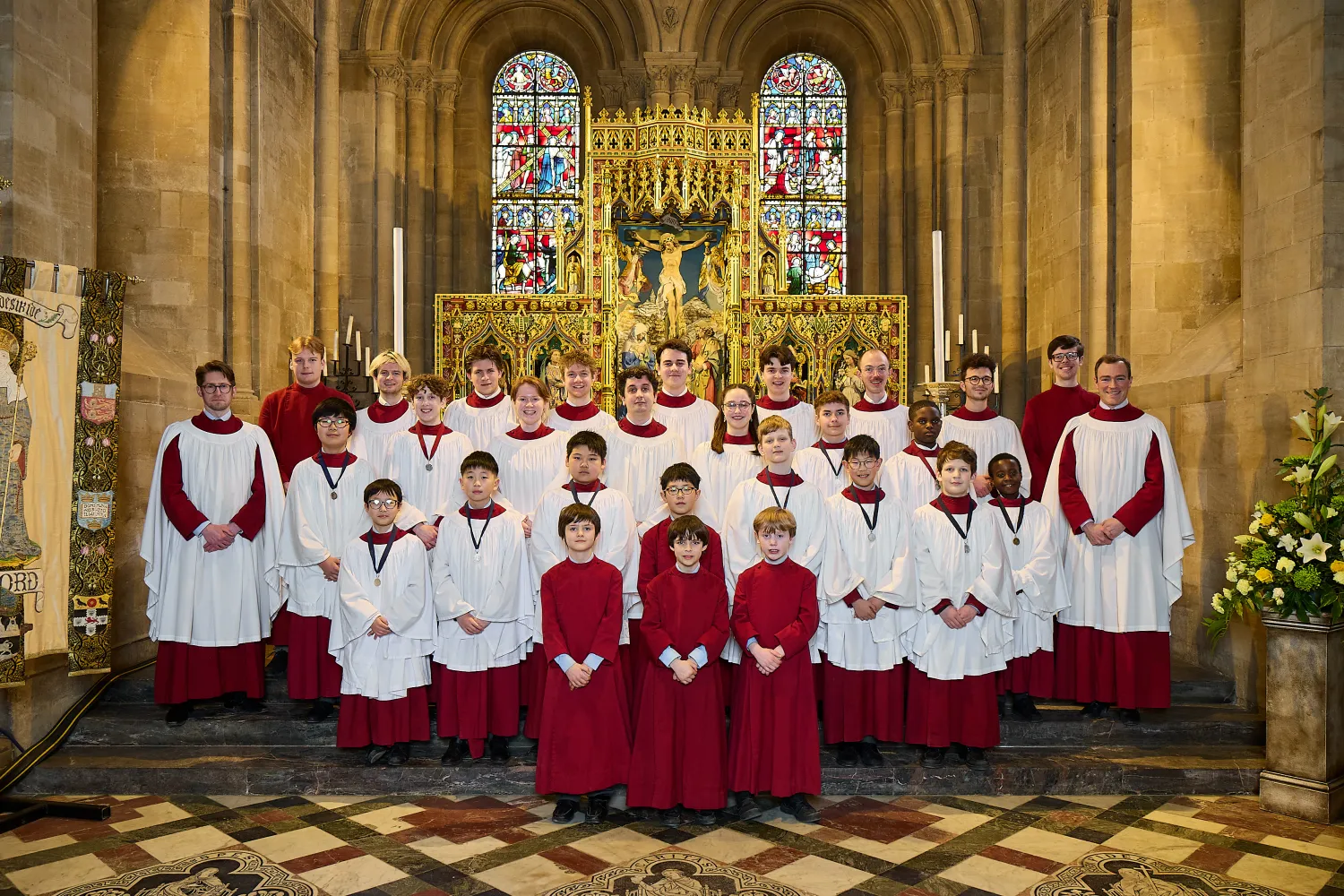 The choir, in their robes, stand in the cathedral sanctuary in a group portrait