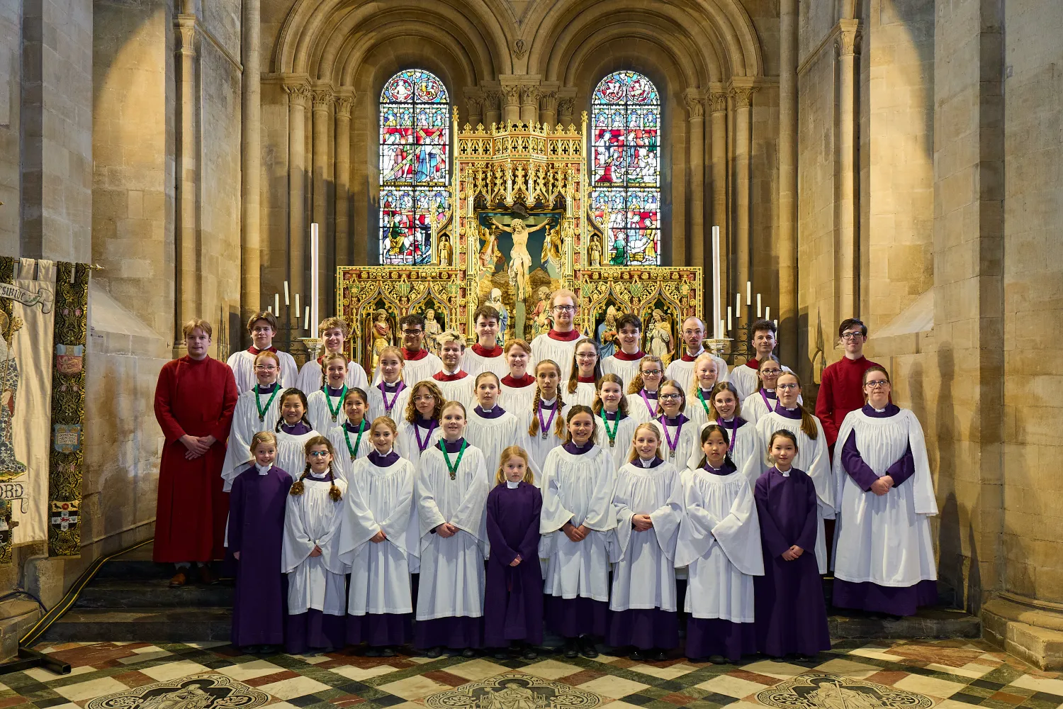 Frideswide Voices, the clerks and organ scholars, arranged in the choir robes in front of the cathedral altar.