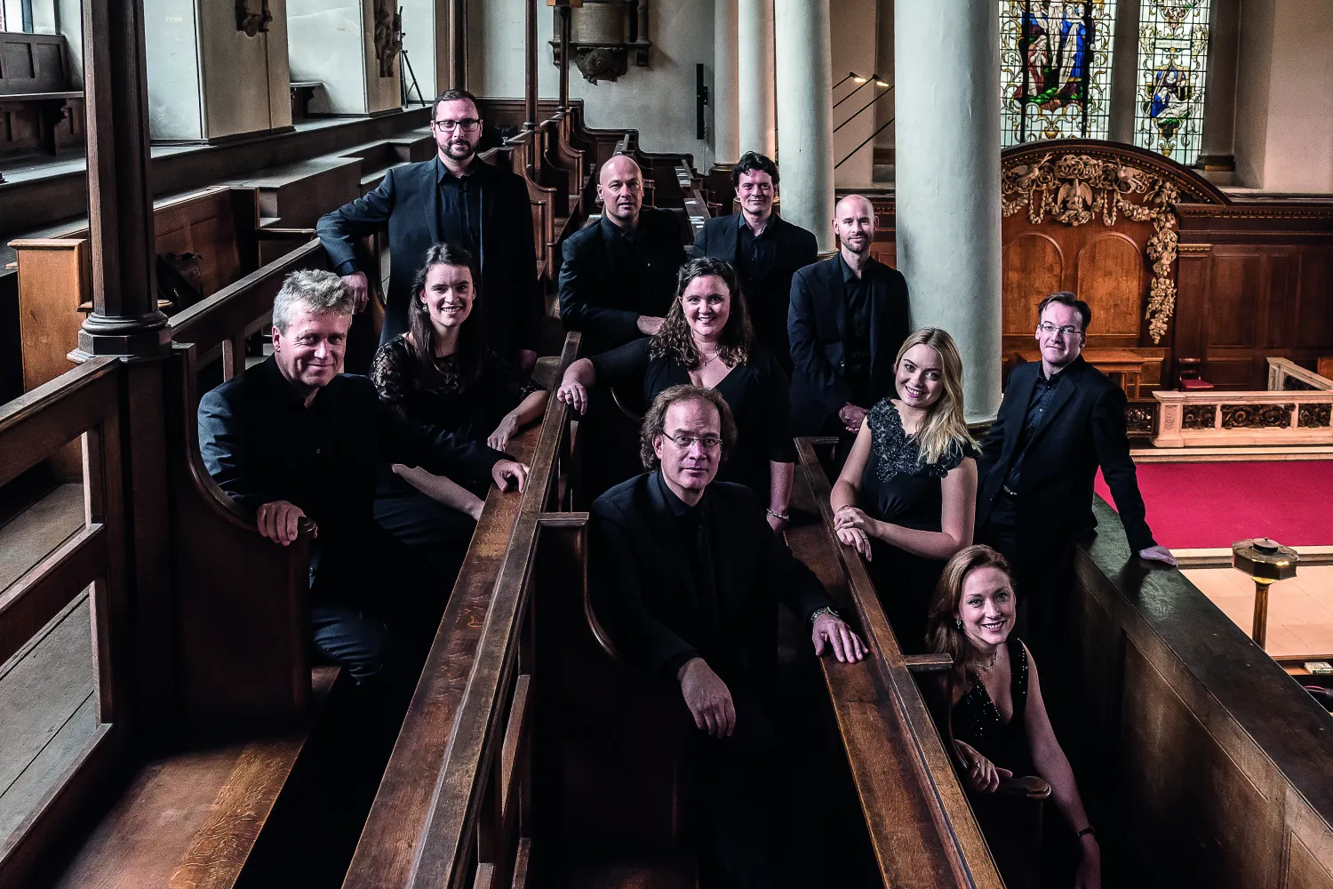 The Alamire choir, sitting and smiling in church pews.