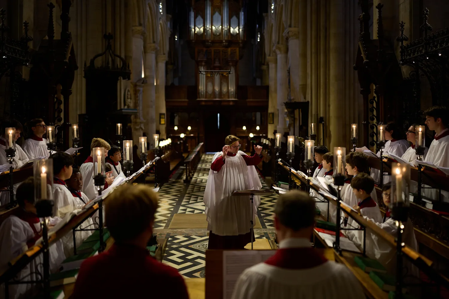 The 2025/26 Cathedral choir performing in an empty cathedral in the choir stalls. They are in their choir rorbes with lit candles