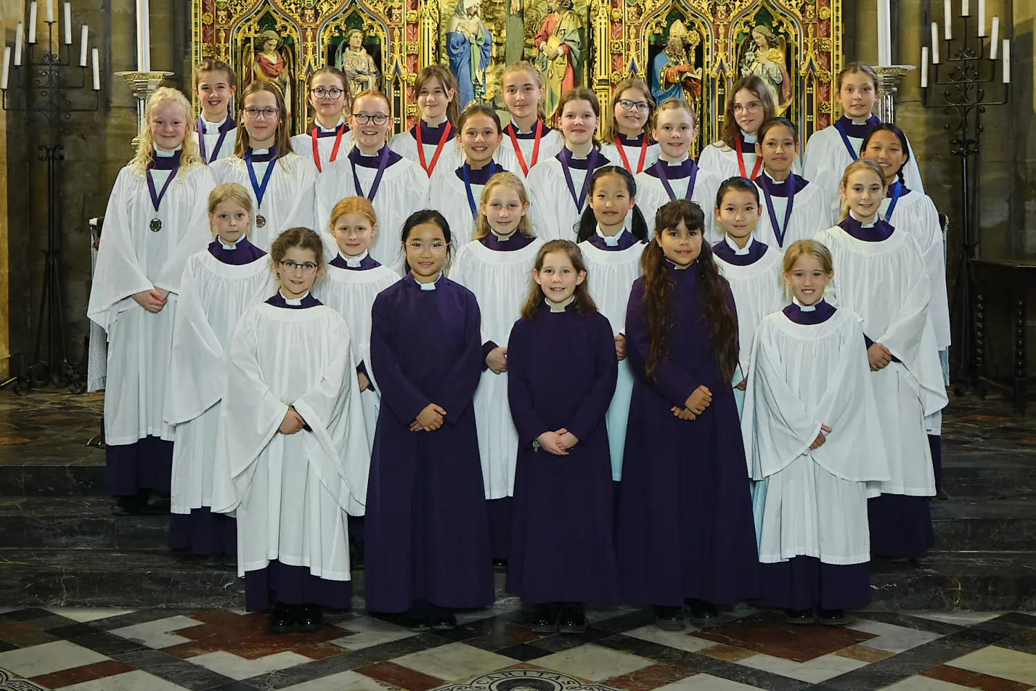 Frideswide Voices choristers in their choir dress gathered by the high altar of Christ Church Cathedral