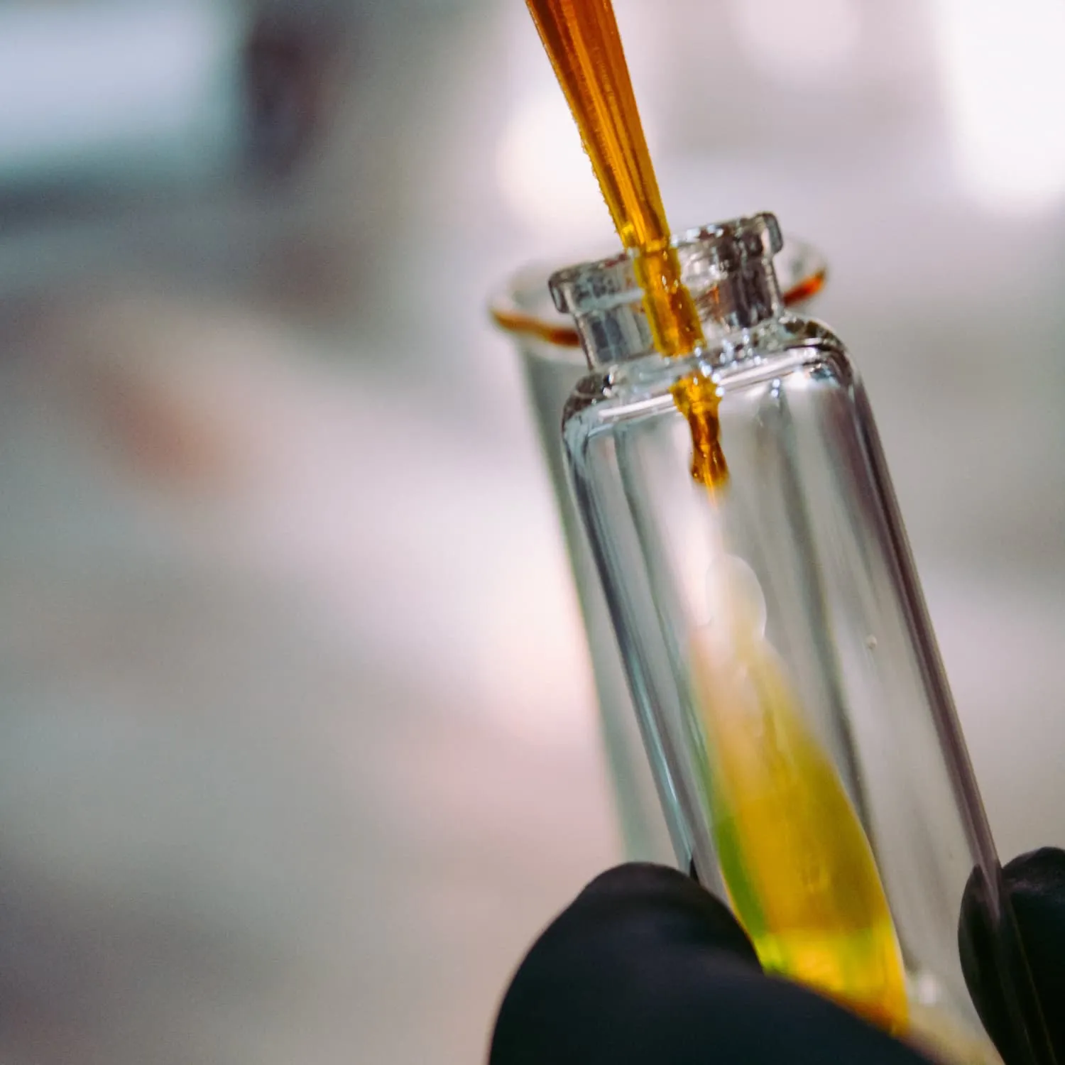 Pipette dropping liquid into glass bottle